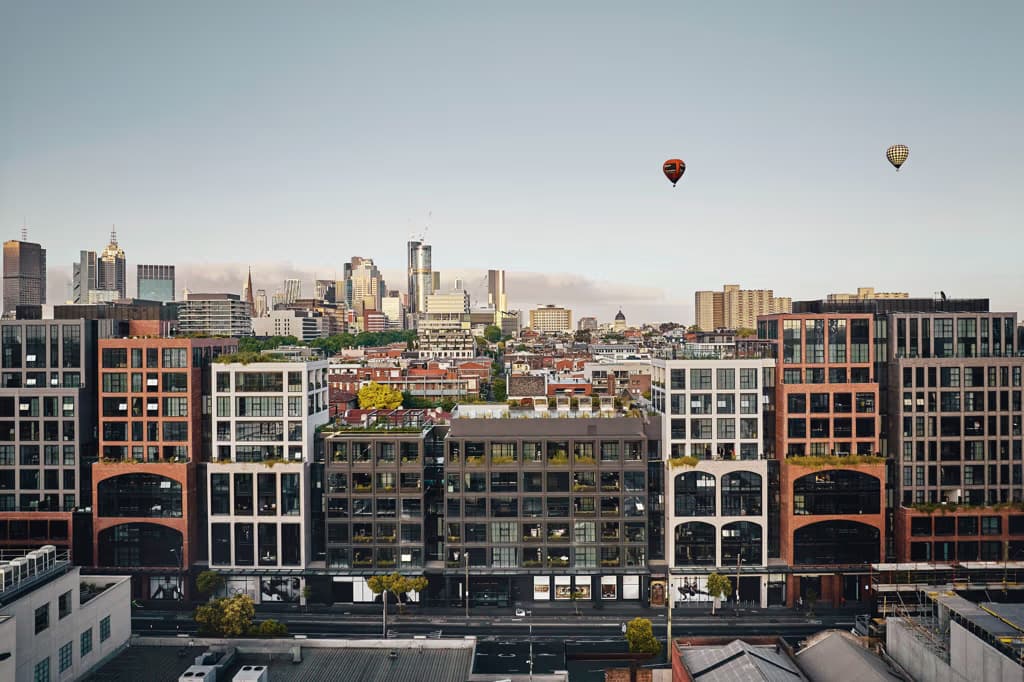 A Melbourne landscape shot of buildings in the foreground and middle ground with 2 hot air balloons in the background
